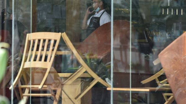 A picture taken March 18, 2020 shows a waiter speaking on his mobile phone inside a closed cafe in Riyadh amid measures to contain the novel COVID-19 coronavirus disease in the desert kingdom. Saudi Arabia called today for a 'virtual' G20 summit over coronavirus. FAYEZ NURELDINE / AFP