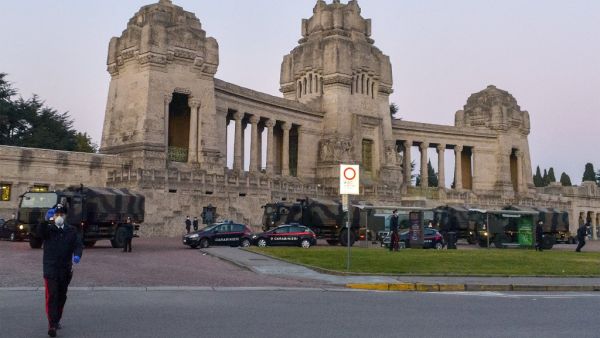 This photo provided by Italian news agency Ansa on March 19, 2020 shows Italian Army trucks parked outside the Monumental cemetery of Bergamo, Lombardy on March 18, 2020, mobilized to transport and bring about sixty coffins to crematoriums in other regions where there are municipalities that have made themselves available to accept them. STRINGER / ANSA / AFP