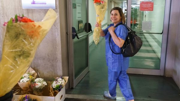 A health worker smiles after receiving a bouquet of flowers from a florist outside the Burgos Hospital (UBU) on March 21, 2020, in Burgos, in northern Spain. Spain reported a 32 percent spike in new deaths from the coronavirus, bringing the country total to 1,326 fatalities, the second highest in Europe after Italy. CESAR MANSO / AFP