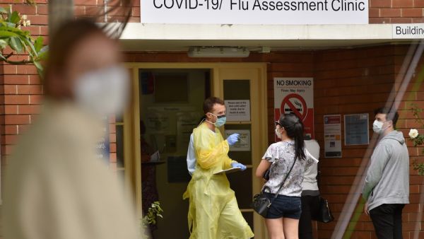 A health worker talks to visitors at a Covid-19 testing centre in Sydney on March 23, 2020. With the imminent closure of pubs, restaurants, cafes and entertainment venues in Sydney, large queues formed outside Australian unemployment benefit offices as online services crashed as the prime minister warned the coronavirus pandemic would cause an economic crisis akin to the Great Depression. PETER PARKS / AFP
