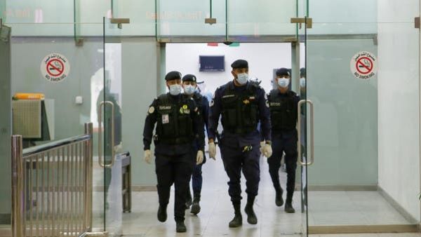 Kuwaiti policemen wearing protective masks wait at Sheikh Saad Airport in Kuwait City, on February 22, 2020, before transferring Kuwaitis arriving from Iran to a hospital to be tested for coronavirus. (File photo: AFP)
