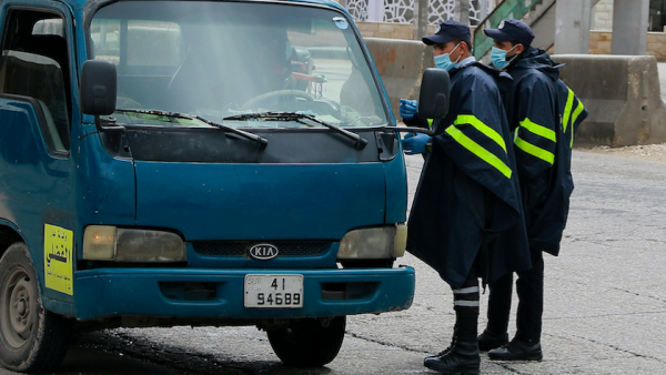 Policemen speak to a truck driver at a checkpoint in the Jordanian capital Amman during a nationawide curfew imposed by the authorities in order to control the spread of the novel coronavirus, on March 21, 2020. Khalil MAZRAAWI / AFP