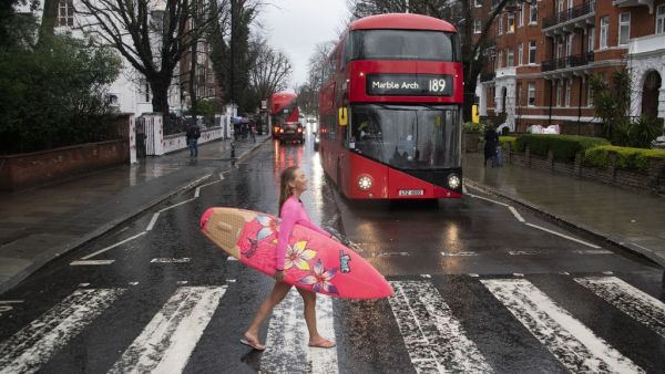 Hawaiian "protest surfer" Alison Teal recreates the famous Beatles Abbey Road album cover as she crosses Abbey Road during a visit to London on March 5, 2020, to raise awareness on the need to combat climate change. (AFP)