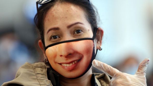 A woman displays her mask as Filipinos who availed general amnesty granted by the Kuwaiti government gather at the Kuwait International Airport Terminal 4, on April 3, 2020 on their home to Manila amid the coronavirus COVID-19 pandemic crisis. For systematic documentations, illegal expats from the Philippines, Egypt, India, Bangladesh, Sri Lanka and other countries were at first, requested to submit themselves at a school compound in Farwaniya arranged according to nationalities. YASSER AL-ZAYYAT / AFP