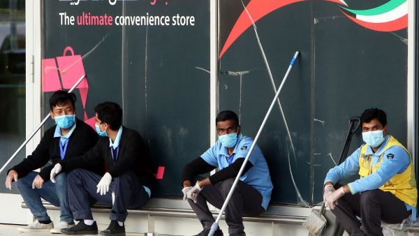 Cleaners wearing facemasks rest at the Kuwait International Airport Terminal 4, on April 3, 2020 amid the coronavirus COVID-19 pandemic crisis. YASSER AL-ZAYYAT / AFP