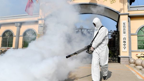 A volunteer sprays disinfectant at a school as the school prepares for students returning after the term opening was delayed due to the COVID-19 coronavirus outbreak, in Shangqiu in China's central Henan province on April 3, 2020. STR / AFP