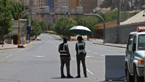 Police officers man a checkpoint in a street in Saudi Arabia's holy city of Mecca on April 3, 2020. Saudi Arabia on April 2 extended curfew restrictions on Islam's two holiest cities to 24 hours to stem the spread of coronavirus as the number of deaths from the disease rose to 21. AFP