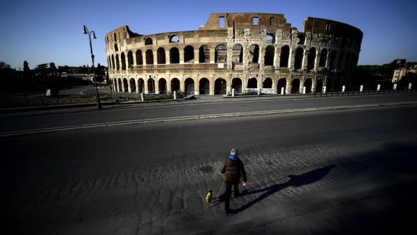 A man walks his dog in front of the Colosseum in central Rome, on April 3, 2020 during the country's lockdown aimed at curbing the spread of the COVID-19 infection, caused by the novel coronavirus. Filippo MONTEFORTE / AFP