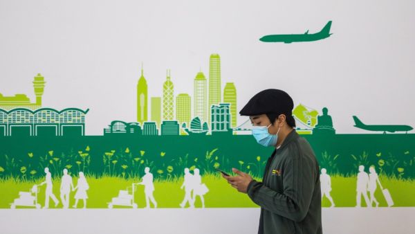 In this picture taken on April 4, 2020, a man wearing a face mask, amid concerns of the COVID-19 coronavirus, walks through the arrivals hall at Hong Kong International Airport. DALE DE LA REY / AFP