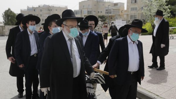 Pallbearers from the Ultra-Orthodox Jewish burial society (Hevrat kadishah), wearing surgical masks as a precaution against COVID-19 coronavirus disease, carry the coffin of an elderly man (not a COVID-19 victim) during a funeral outside the Shamgar funeral house in Jerusalem on April 5, 2020. MENAHEM KAHANA / AFP