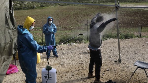 An employee at the Palestinian ministry of health sprays disinfectant on a worker returning from Israel through the Tarqumiah crossing, north-west of the West Bank city Hebron, on April 6, 2020, to stem the spread of the COVID-19 pandemic. HAZEM BADER / AFP