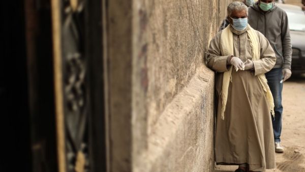Egyptian men wearing masks wait outside a centre of non-governmental organisation Egyptian Food Bank to receive cartons with foodstuffs on April 05, 2020, as the charity distributes aid to people who lost their jobs due to the coronavirus pandemic crisis, in the Egyptian capital Cairo. The large Cairo-based charity organisation EFB has been at the forefront of a public relief effort in the most populous Arab country, where one third of the population of over 100 million lives in poverty, surviving on about 
