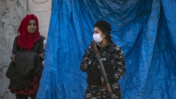 A member of Kurdish Internal Security wearing a protective mask stands guard as Kurdish Red Crescent medics check a passenger for COVID-19 symptoms upon arrival from the Syrian capital, at a mobile site just outside Syria's Qamishli airport in the northeastern Hasakeh province, on April 7, 2020. AFP/File