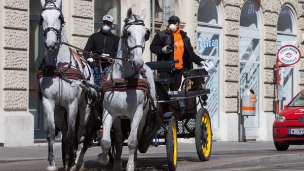 A horse-drawn carriage turns at an intersection in the 3rd district in Vienna, Austria on April 8, 2020. The Hotel Intercontinental cooks up to 350 lunches a day for people in need who are unable to feed themselves due to the coronavirus pandemic. The meals are delivered voluntarily by fiaker drivers. ALEX HALADA / AFP