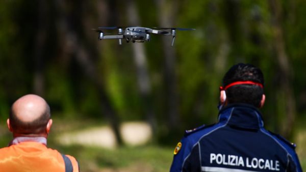An officer of the municipal police (R), assisted by an instructor, pilots a DJI Mavic 2 Enterprise drone equipped with a thermal sensor for checking people's temperature on April 9, 2020 in Treviolo, near Bergamo, during the country's lockdown aimed at stopping the spread of the COVID-19 pandemic, caused by the novel coronavirus. Miguel MEDINA / AFP