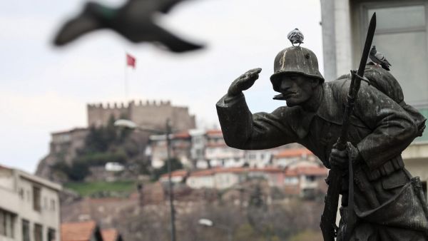 A pigeon flies next to a statue of a soldier on Ulus square, with the Ankara Castle in the background, in Ankara, on April 11, 2020, during the 48-hour curfew imposed by the government to stem the spread of the novel coronavirus (COVID-19).  Adem ALTAN / AFP