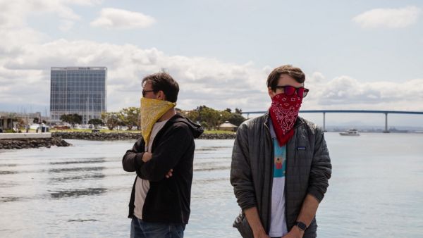 Two men wearing bandanas to protect their face against the COVID-19, Coronavirus outbreak wait for their order at the Tuna Harbor Dockside Market in San Diego, California on April 11, 2020. Due to the Covid-19, Coronavirus pandemic, fisherman had to regroup to stay afloat and lower their cost for the locals who have been purchasing their fish since local restaurants have been shut down. ARIANA DREHSLER / AFP