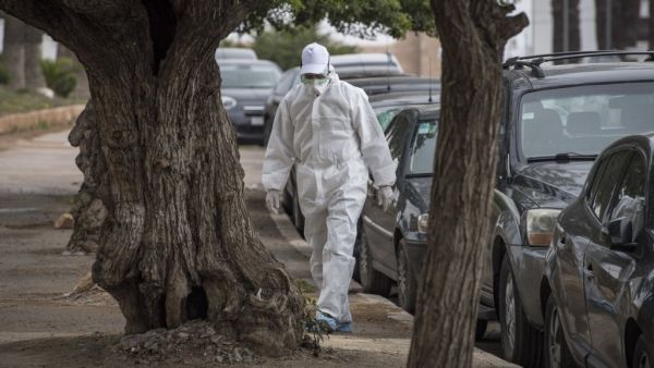 A Moroccan health worker wearing a protective outfit against the novel coronavirus walks in an empty street in the capital Rabat on April 12, 2020. FADEL SENNA / AFP