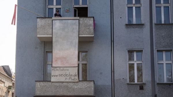 Berlin-based Polish artist Isabella Sedeka stands on her balcony as she displays her work, part of the "Balconies, Life, Art, Pandemic, and Proximity" exhibition, in Berlin on April 12, 2020, amid a new coronavirus COVID-19 pandemic.. AFP/File