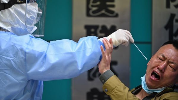 A man being tested for the COVID-19 novel coronavirus reacts as a medical worker takes a swab sample in Wuhan in China's central Hubei province on April 16, 2020. China has largely brought the coronavirus under control within its borders since the outbreak first emerged in the city of Wuhan late last year. Hector RETAMAL / AFP
