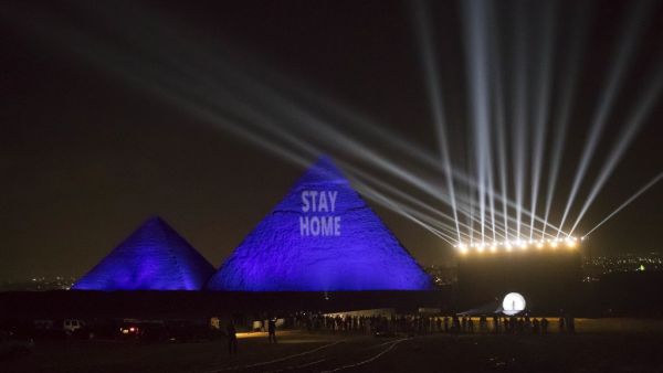 A picture taken on April 18, 2020 show the Great pyramids lighten-up with blue light and reading with a laser projection the message "Stay Home" on the Giza plateau outside the Egyptian capital of Cairo, on the world heritage day, as the country fights against the spread of the COVID-19, (the novel coronavirus). Khaled DESOUKI / AFP