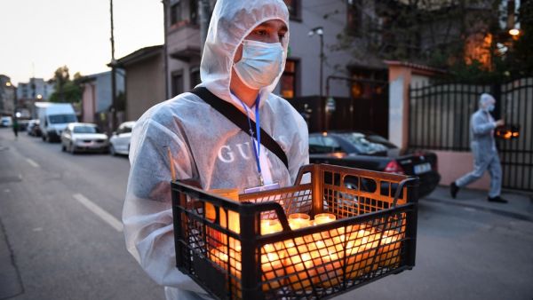 A church volunteer wearing protective equipment brings holy light to the people at their home during Christian Orthodox Easter celebration prior to the religious service held with closed doors due to the social distancing rules imposed by the state of emergency in Bucharest April 18, 2020, amid the COVID-19 pandemic caused by the novel coronavirus. Until now Romania registered 8,418 confirmed cases of people infected by coronavirus, 421 deaths and 1,730 healed persons. Daniel MIHAILESCU / AFP