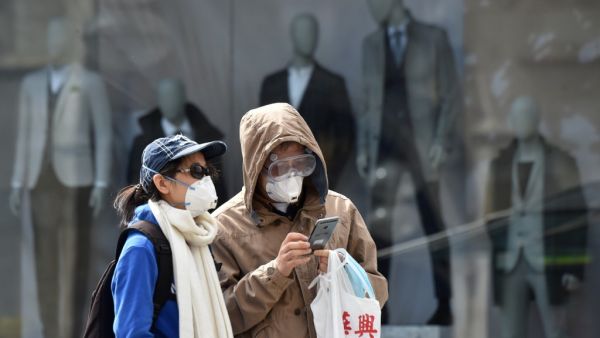 People wear face masks as they walk on a street on April 21, 2020 in front of closed stores in Munich, southern Germany, amid the new coronavirus COVID-19 pandemic. Christof STACHE / AFP