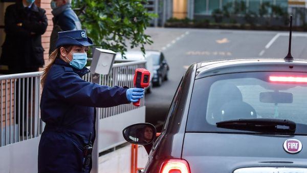 A security agent (L) scans the body temperature of an employee of Italian automobile manufacturer Fiat arriving by car at the Mirafiori plant in Turin, as work resumes on April 27, 2020 after the government laid out partial reopening plans. (AFP)