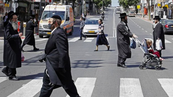 Ultra-Orthodox Jews, some of them wearing masks, cross a street in the religious Israeli city of Bnei Brak, near Tel Aviv, on March 3, 2020 during the novel coronavirus pandemic crisis. (AFP)