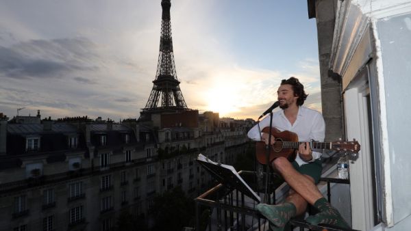 Singer Adrien Pelon aka "Adri1" performs from his balcony for his neighborhood on May 2, 2020, in Paris, as the country is under lockdown to stop the spread of the Covid-19 pandemic caused by the novel coronavirus. Ludovic MARIN / AFP