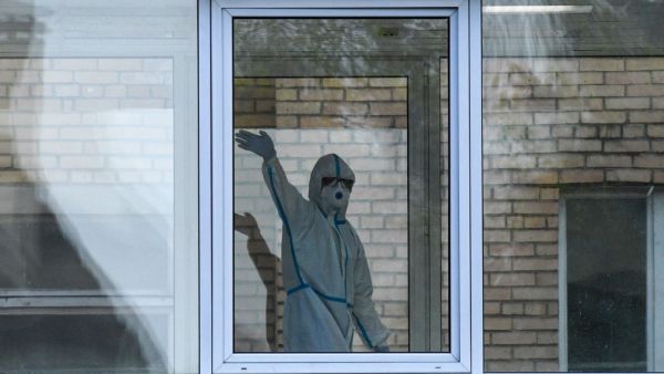 A health worker wearing protective equipment waves behind a window inside a hospital where patients infected with the COVID-19 are being treated in Khimki, outside Moscow on May 3, 2020 amid the COVID-19 outbreak, caused by the novel coronavirus. Russia on May 3, 2020 reported its largest increase in coronavirus cases with the new infections rising by more 10,000 in a single day. Kirill KUDRYAVTSEV / AFP