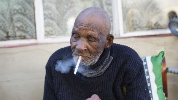 Fredie Blom enjoys a cigarette as he celebrates his 116th birthday at his home in Delft, near Cape Town, on May 8, 2020. According to 'Oupa' (grandfather) Fredie and his identity card, he was born in 1904, making him one of the oldest men in the world. RODGER BOSCH / AFP