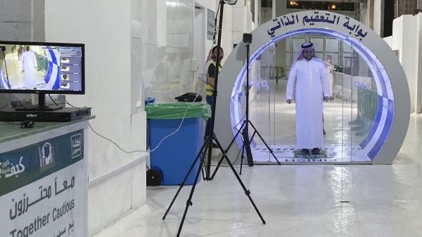 A man passes through a self-sterilisation gate set up at an entrance of the Kaaba and the Grand Mosque, as a preventive measure amid the the COVID-19 pandemic during the Muslim month of Ramadan in the Saudi holy city of Mecca, on May 8, 2020. Saudi Authorities allowed for a limited number of worshippers to enter the Grand Mosque to perform prayers during Ramadan, amid unprecedented bans on family gatherings and mass prayers due to the novel coronavirus (COVID-19) pandemic. STR / AFP