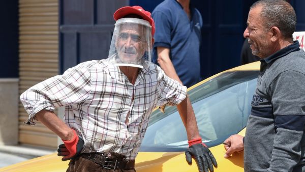 A Tunisian man wearing protective gear amid the COVID-19 pandemic looks on as he chats with another on a street in the Kram area of the capital Tunis on May 8, 2020, as authorities begin a gradual sector and region-based process to mitigate lockdown measures. FETHI BELAID / AFP