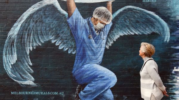A woman looks at a mural of a health worker with wings holding a globe on International Nurses Day in Melbourne on May 12, 2020. As frontline hospital staff are constantly facing the risks from the COVID-19 coronavirus outbreak, the world is marking International Nurses Day, celebrated around the world every May 12, the anniversary of Florence Nightingale's birth. William WEST / AFP