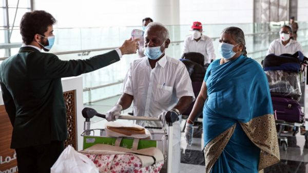 Indian nationals residing in Oman, wearing face masks due to the COVID-19 coronavirus pandemic, have their body temperatures measured at a terminal in Muscat International Airport ahead of their repatriation flight from the Omani capital, on May 12, 2020. MOHAMMED MAHJOUB / AFP