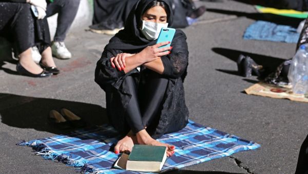 An Iranian woman wearing a face mask against the Covid-19 coronavirus attends Laylat al-Qadr prayers, one of the holiest nights during the Muslim fasting month of Ramadan, outside a mosque in the Tehran, on May 13, 2020. ATTA KENARE / AFP
