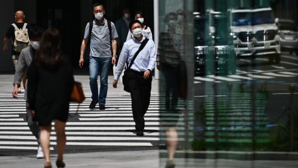 People wearing face masks amid the COVID-19 coronavirus outbreak walk across a street in Tokyo on May 13, 2020. Charly TRIBALLEAU / AFP