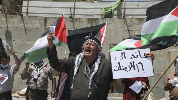 Mask-clad Palestinians demonstrate along the controversial separation barrier at the western entrance of the northern West Bank city of Tulkarem on May 16, 2020, marking the 72nd anniversary of Nakba (catastrophe). (AFP/File)