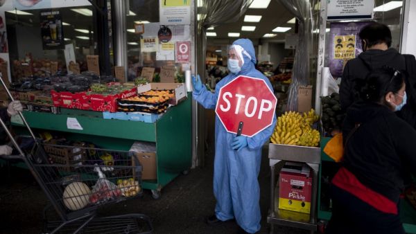 A worker wearing a full body suit holds a STOP sign in front of a Food market as he manages the flow of the customers on May 18, 2020 in the Jackson Heights neighbourhood of Queens in New York City. Johannes EISELE / AFP
