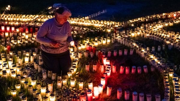 60-year-old Gertrud Schop lights candles arranged in the shape of a cross, with one candle dedicated to each of the more than 8,000 German Covid-19-related victims, in Zella-Mehlis, eastern Germany on May 19, 2020, amid the novel coronavirus / COVID-19 pandemic. Schop is planning to continue the project until a vaccine against Covid-19 is available. JENS SCHLUETER / AFP