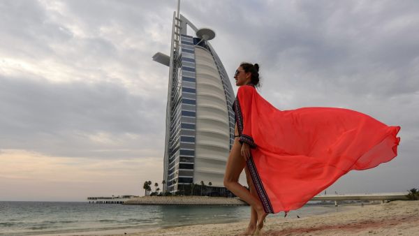 A woman bather walks along the beach shoreline near the Burj al-Arab hotel in Dubai on May 20, 2020, as COVID-19 coronavirus pandemic lockdown measures are eased in the Gulf emirate. Karim SAHIB / AFP