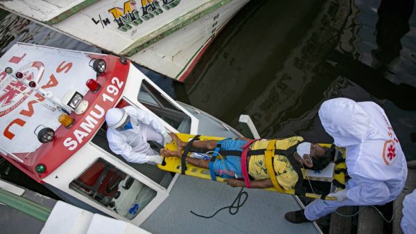 Health personnel of a medical emergency response service carry Brazilian Eladio Lopes, 79, -infected with the new coronavirus- on a stretcher to be transferred on an ambulance boat from the community of Portel to a hospital in Breves, on Marajo island, Para state, Brazil, on May 25, 2020. Ambulance boat services allow critical COVID-19 patients to be tranferred in very remote areas surrounded by water in Brazil. TARSO SARRAF / AFP