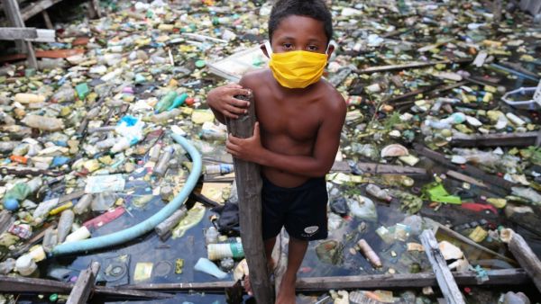 A boy from the Educandos riverside community wears a face mask during the COVID-19 coronavirus pandemic in Manaus, the Amazon on May 26, 2020. The Nossa Senhora Perpetuo Socorro church has been handing out masks to impoverished members of its community to assist in the fight against the spread of the novel coronavirus. MICHAEL DANTAS / AFP