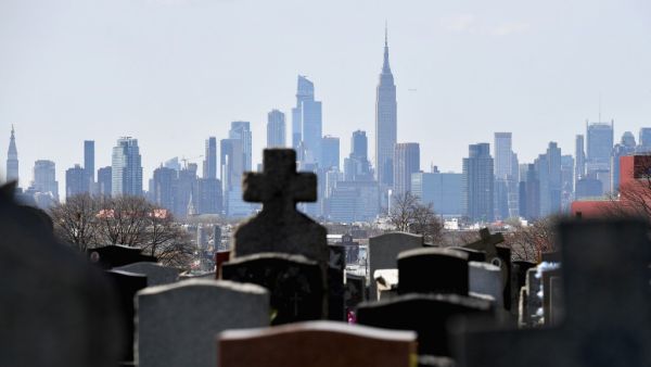 In this file photo Gravestones from Linden Hill Methodist Cemetery are seen with the Manhattan skyline in the background in Brooklyn, New York. The United States has now recorded more than 100,000 coronavirus-related deaths, Johns Hopkins University reported Wednesday -- a somber milestone and by far the highest total in the world. The country reported its first death about three months ago. Since then, nearly 1.7 million infections have been tallied nationwide, according to the Baltimore-based school. The 