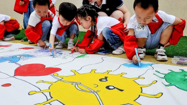 Childern draw an image showing people's efforts against the COVID-19 coronavirus at a kindergarten during the Childern's Day in Shangrao in China's central Jiangxi province on June 1, 2020. STR / AFP