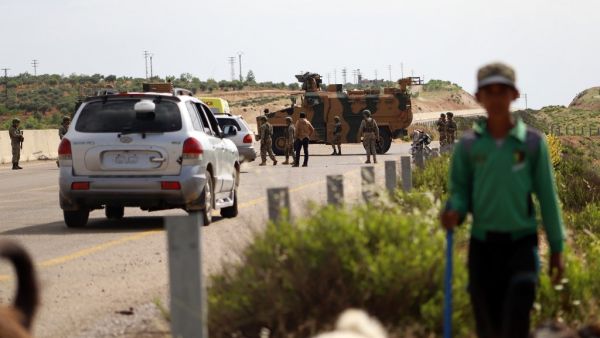 A shepherd boy leads his flock near Turkish soldiers standing outside an armoured vehicle part of a joint Turkish-Russian military patrol along the M4 highway in Ariha in the rebel-held northwestern Syrian province of Idlib on June 2, 2020. Abdulaziz KETAZ / AFP