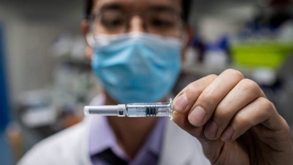 This file photo taken on April 29, 2020 shows an engineer displaying an experimental vaccine for the COVID-19 coronavirus that was tested at the Quality Control Laboratory at the Sinovac Biotech facilities in Beijing. China has mobilised its army and fast-tracked tests in the global race to find a coronavirus vaccine, and is involved in several of the dozen or so international clinical trials currently under way. NICOLAS ASFOURI / AFP
