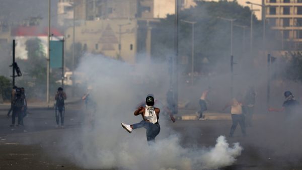A Lebanese protester kicks a tear gas canister amid clashes with riot police following a demonstration in central Beirut, on June 6, 2020. Protesters poured into the streets of the Lebanese capital to decry the collapse of the economy, as clashes erupted between supporters and opponents of the Iran-backed Shiite group Hezbollah. PATRICK BAZ / AFP