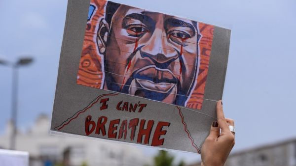 A woman holds a placard depicting George Floyd's face and reading "I can't breathe" in Bordeaux, on June 9, 2020, during a demonstration against racism and police brutality in the wake of the death of George Floyd, an unarmed black man killed while apprehended by police in Minneapolis. NICOLAS TUCAT / AFP